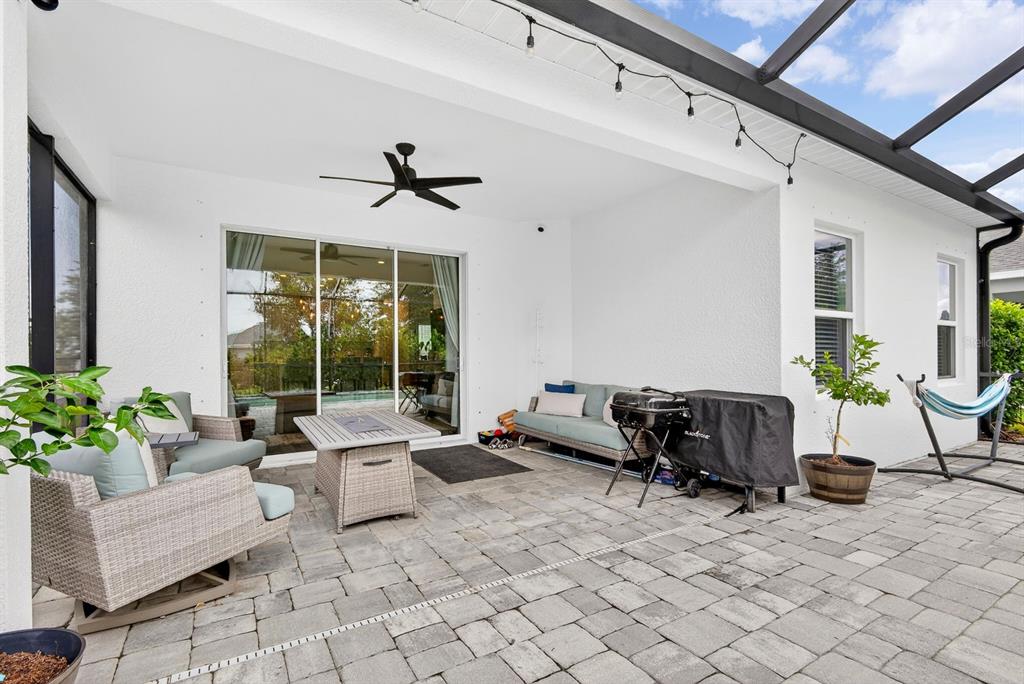A covered patio features paver flooring, outdoor furniture, a grill, and a ceiling fan — 13852 OLD CREEK COURT, PARRISH, FL