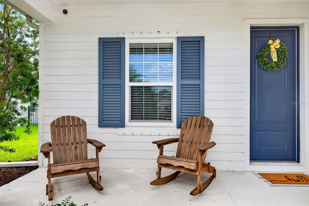 A front porch features two wooden rocking chairs, a blue door, and a window — 13852 OLD CREEK COURT, PARRISH, FL