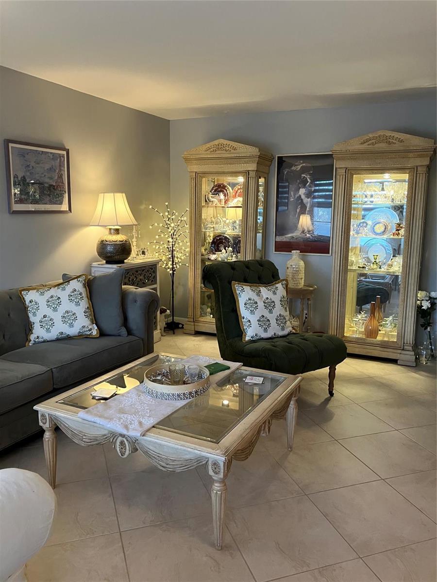 A living room features a grey sofa, green tufted chair, glass coffee table, and two cabinets — 284 Grantham F, Deerfield Beach FL 33442, DEERFIELD BEACH, FL
