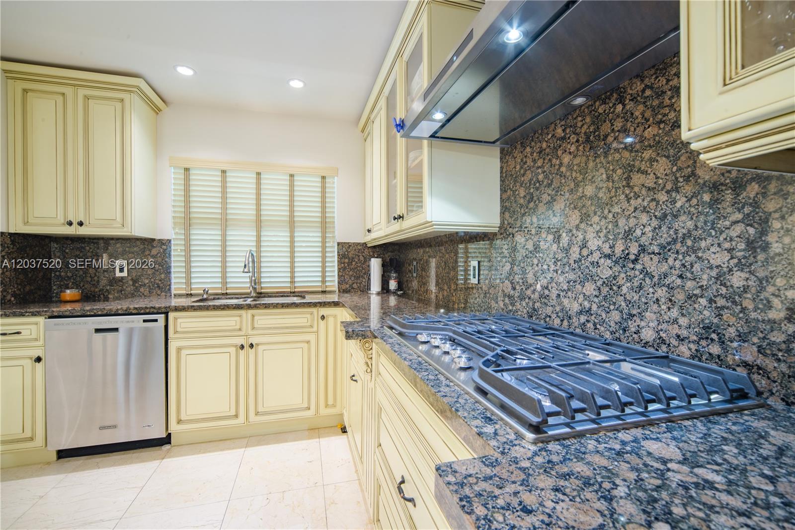 A kitchen features cream-colored cabinets, granite countertops, a gas cooktop, and stainless steel appliances — 3514 Crystal Ct, Miami FL 33133, MIAMI, FL
