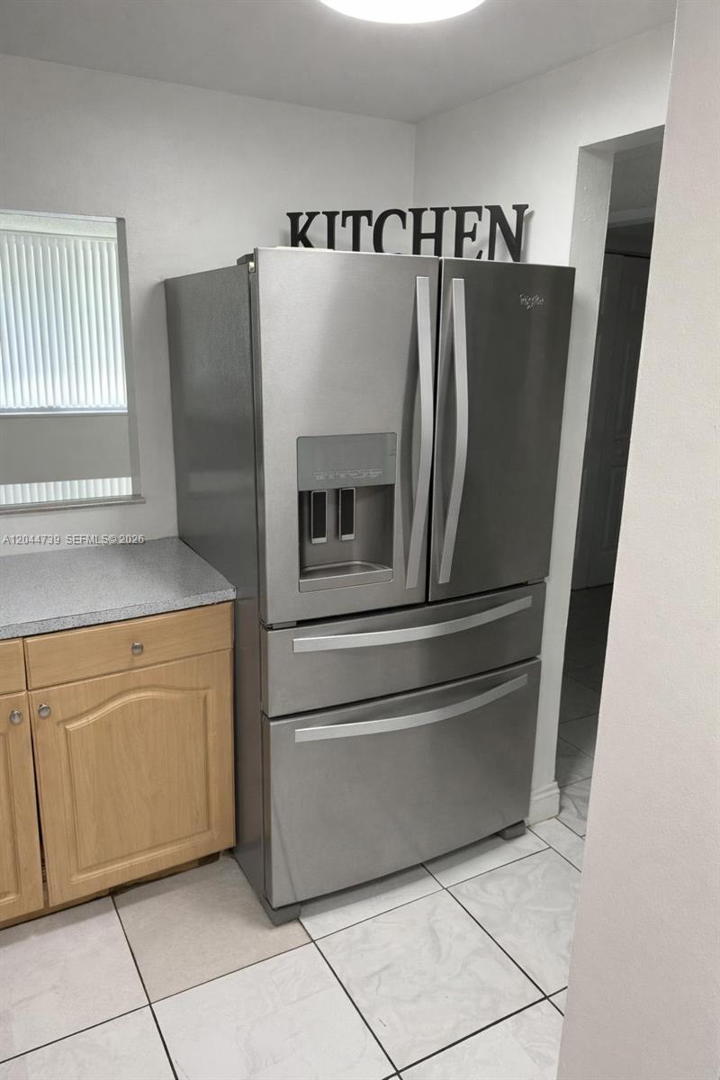 A stainless steel French door refrigerator stands in a kitchen with light-colored tile flooring — 10090 NW 80th Ct # 1540, Hialeah Gardens FL 33016, HIALEAH GARDENS, FL