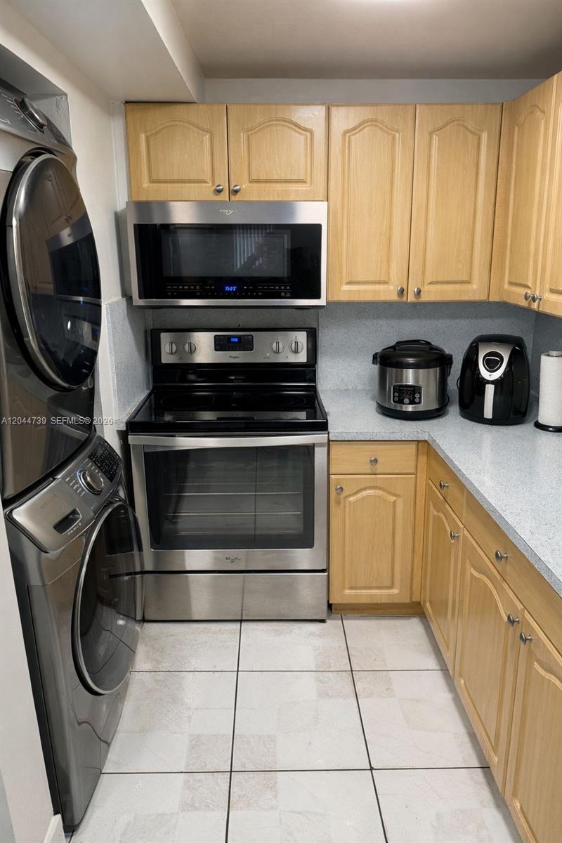 A kitchen features light wood cabinets, stainless steel appliances, and a stacked washer and dryer — 10090 NW 80th Ct # 1540, Hialeah Gardens FL 33016, HIALEAH GARDENS, FL