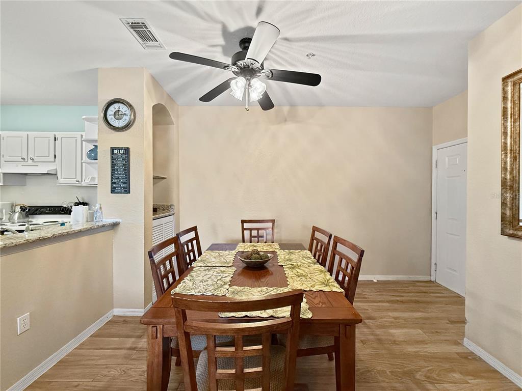 A dining area features a wooden table with six chairs, a ceiling fan, and light flooring — 8815 DUNES COURT UNIT 105, KISSIMMEE, FL
