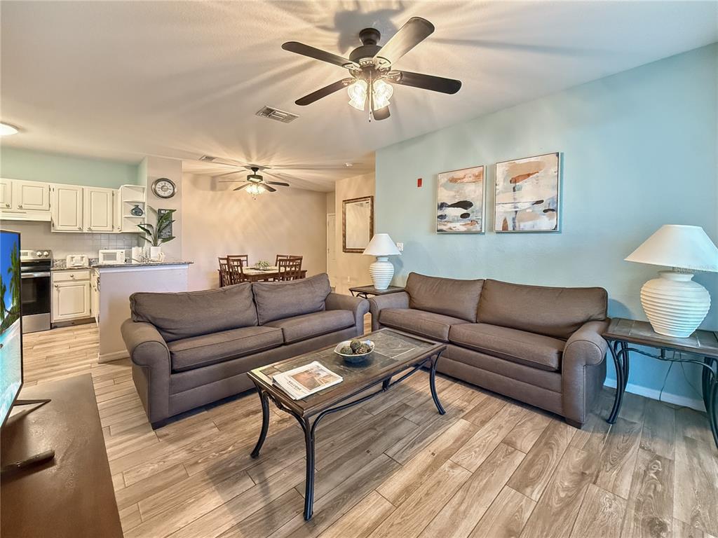A living room features two brown sofas, a coffee table, and light wood-look flooring — 8815 DUNES COURT UNIT 105, KISSIMMEE, FL