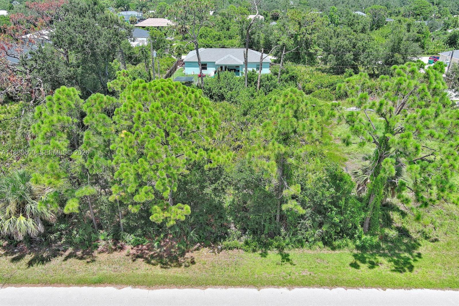 An aerial view shows a wooded, undeveloped lot in front of a single-story house — 11944 Brookside Ave, Port Charlotte FL 33981, PORT CHARLOTTE, FL