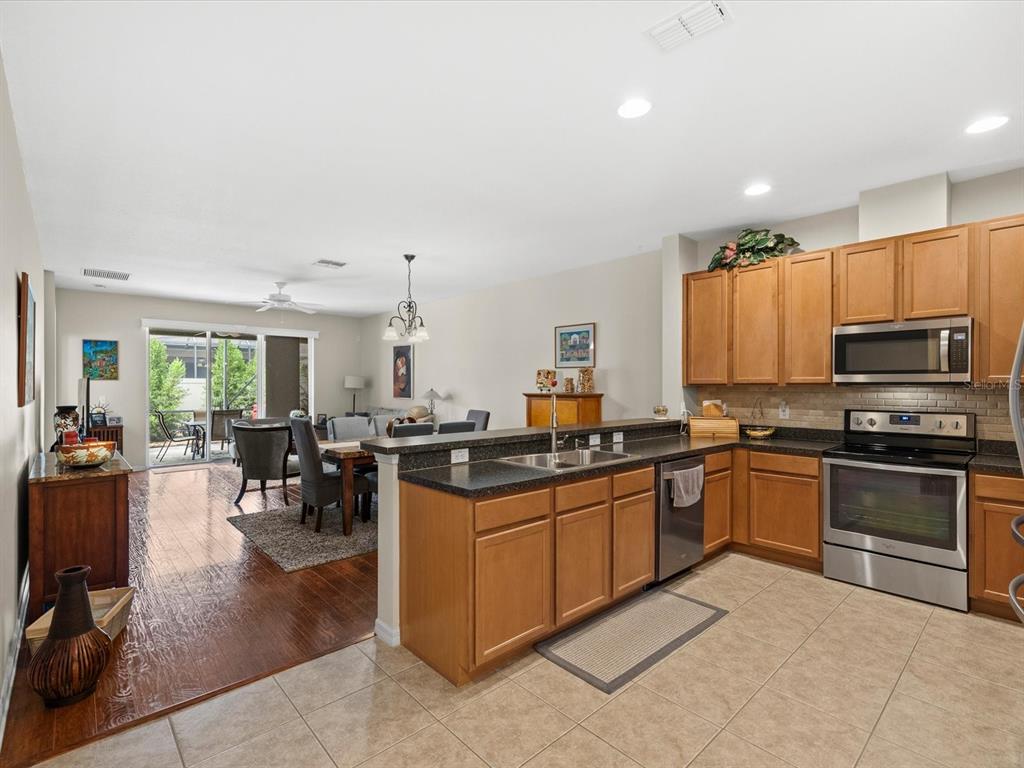 A kitchen with wood cabinets and dark countertops overlooks a dining area with hardwood floors — 2239 BARRACUDA COURT, HOLIDAY, FL