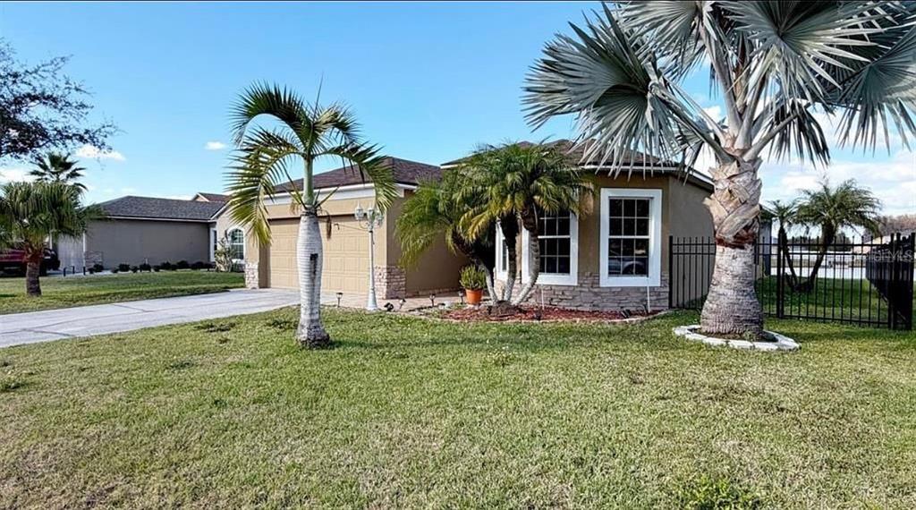 A single-story house with a tan exterior, a two-car garage, and several palm trees — 4619 CABALERRO TRAIL, KISSIMMEE, FL