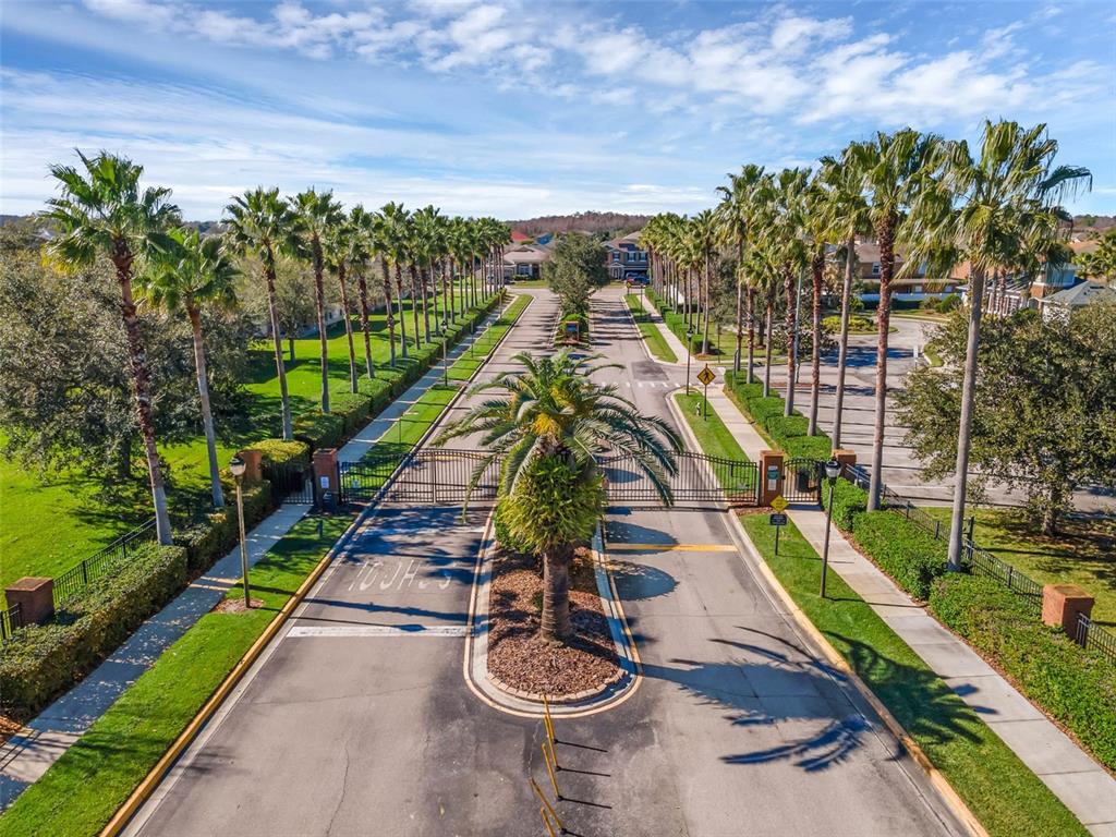 An aerial view of a gated residential community entrance lined with numerous tall palm trees — 4619 CABALERRO TRAIL, KISSIMMEE, FL