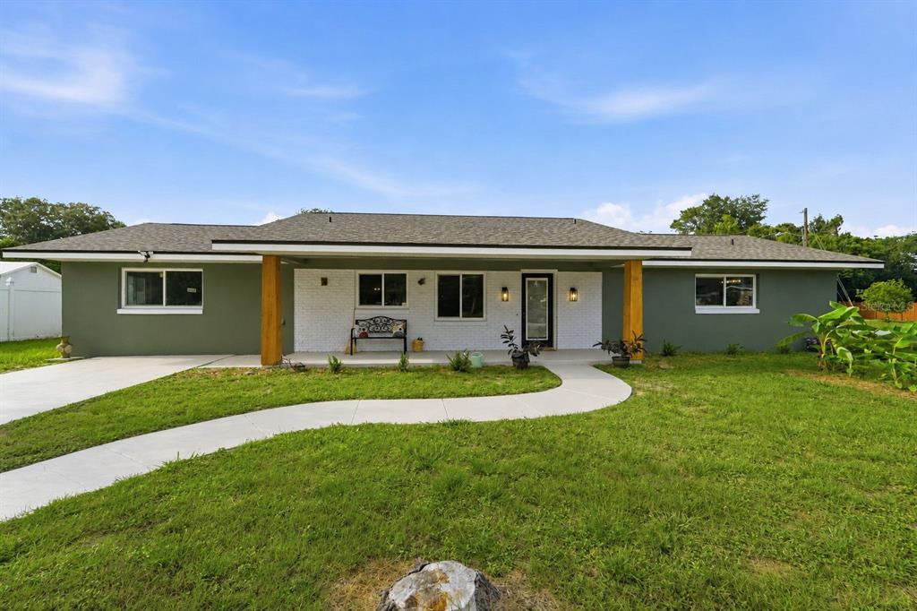 A single-story house with olive green siding, a white brick facade, and a covered porch — 525 E ROBERTS STREET, ORANGE CITY, FL