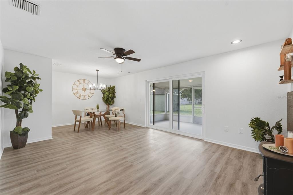 A bright dining and living area features wood-look flooring, a ceiling fan, and sliding doors — 525 E ROBERTS STREET, ORANGE CITY, FL