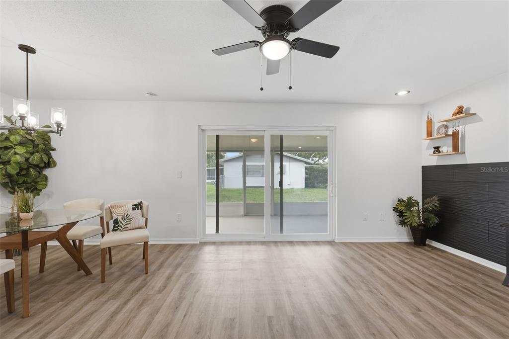 A dining area with wood-look flooring, a sliding glass door, and a black accent wall — 525 E ROBERTS STREET, ORANGE CITY, FL