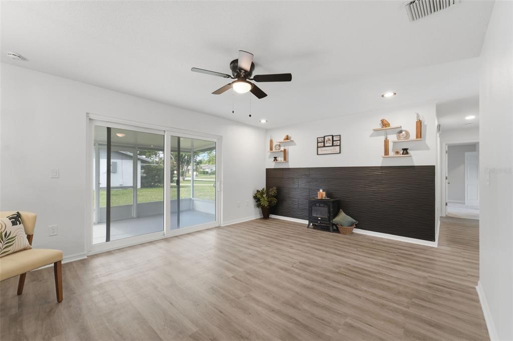 A living room features wood-look flooring, a dark textured accent wall, and sliding glass doors — 525 E ROBERTS STREET, ORANGE CITY, FL