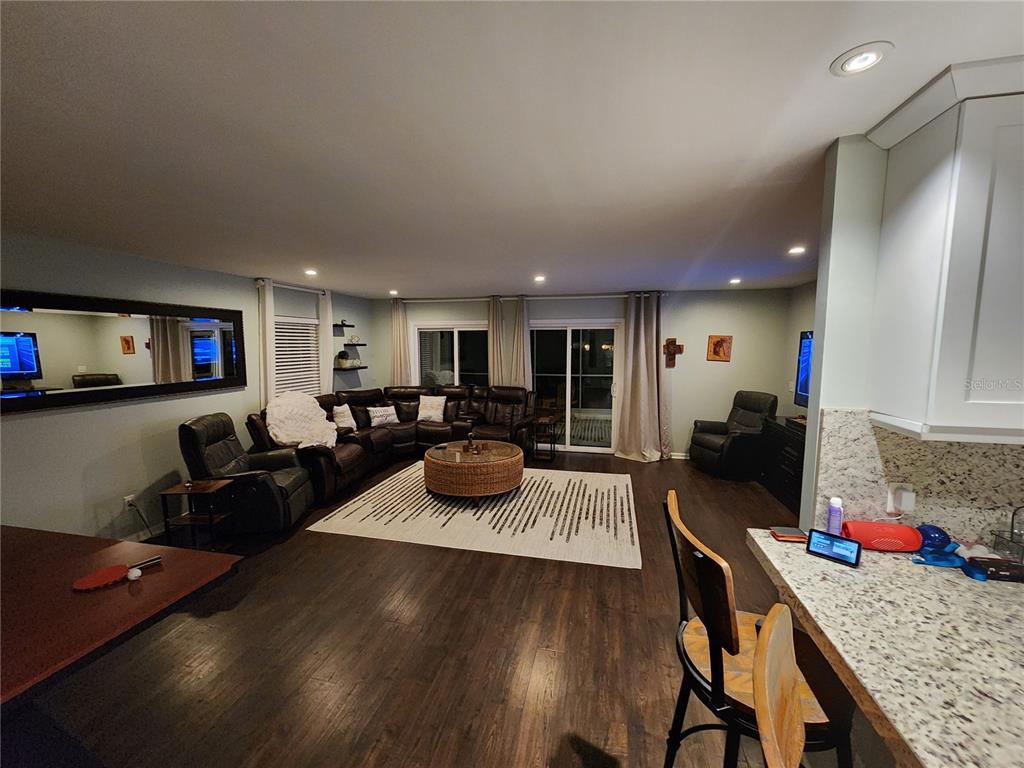 A living room with dark wood floors, a large sectional sofa, and a kitchen counter — 149 SEA ISLE CIRCLE, SOUTH DAYTONA, FL