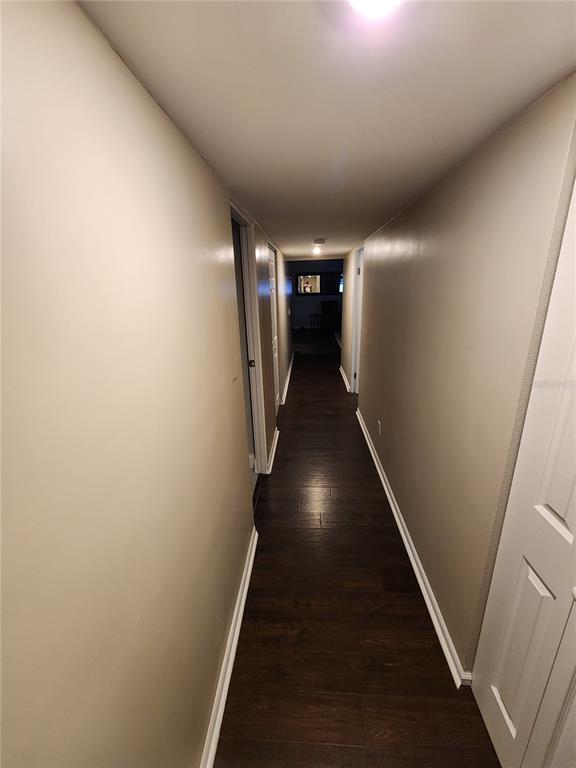 A narrow hallway features dark wood-look flooring, beige walls, and white trim — 149 SEA ISLE CIRCLE, SOUTH DAYTONA, FL