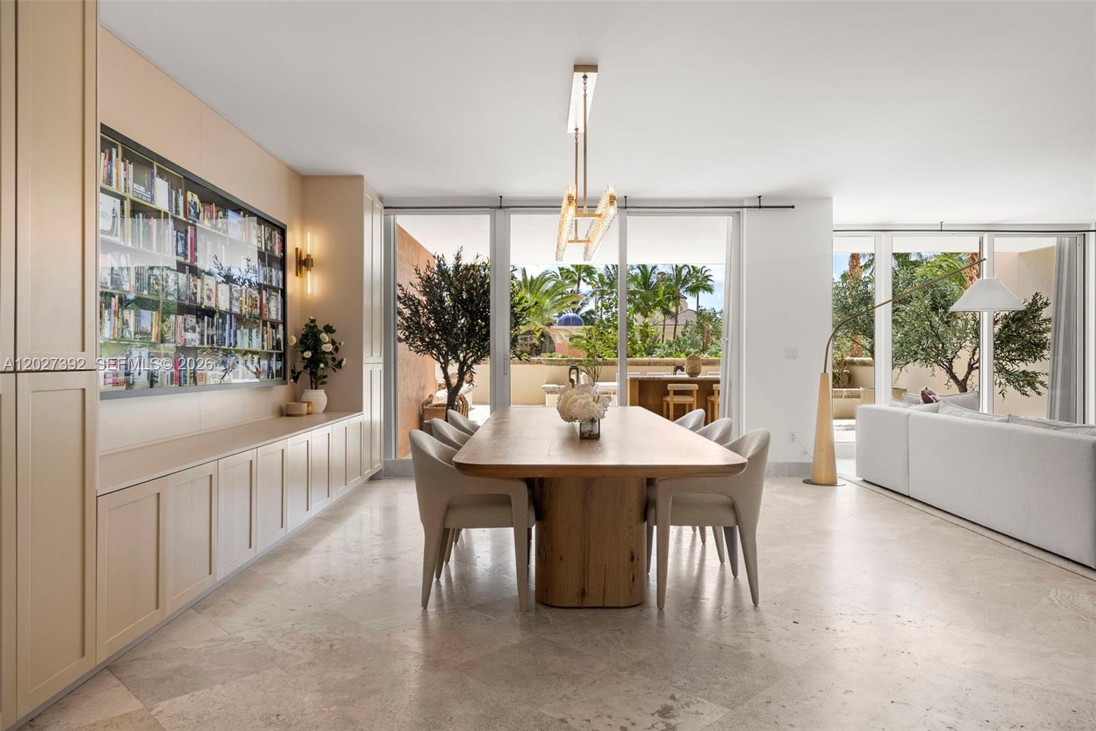 A dining room features a long wooden table, built-in cabinetry, and sliding glass doors to a patio — 785 Crandon Blvd, Key Biscayne FL 33149, KEY BISCAYNE, FL