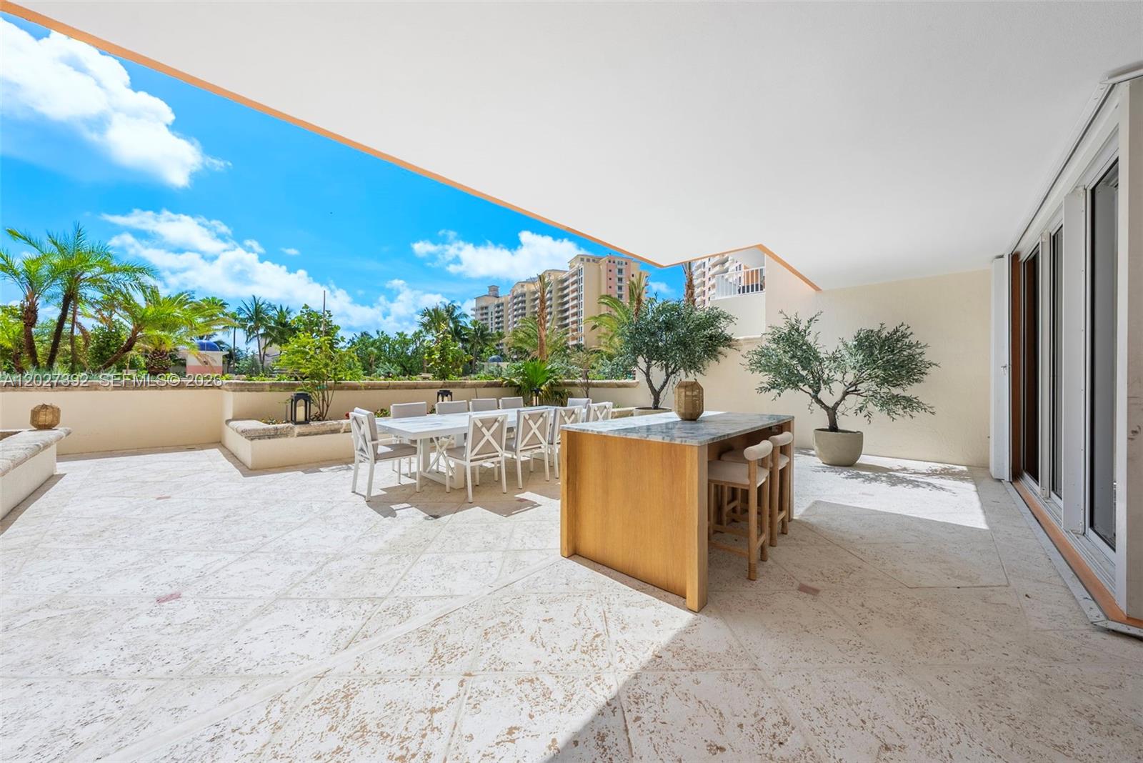 A spacious outdoor terrace features a dining set, a kitchen island, and tropical landscaping — 785 Crandon Blvd, Key Biscayne FL 33149, KEY BISCAYNE, FL