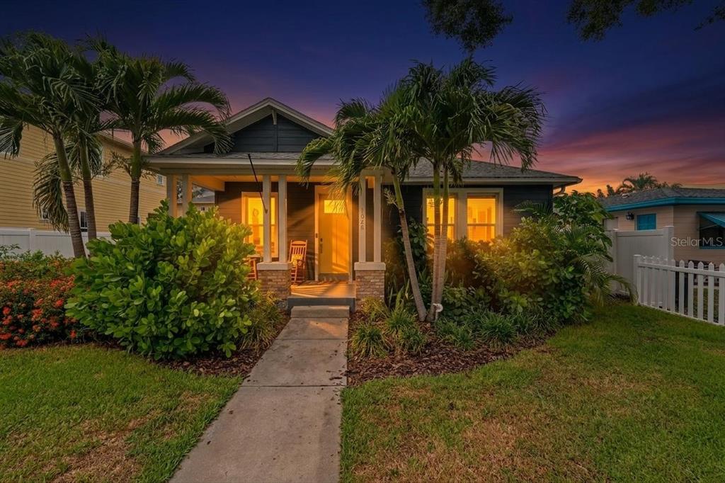 A dark-sided bungalow with a front porch and palm trees at dusk — 1028 5TH STREET N, ST PETERSBURG, FL