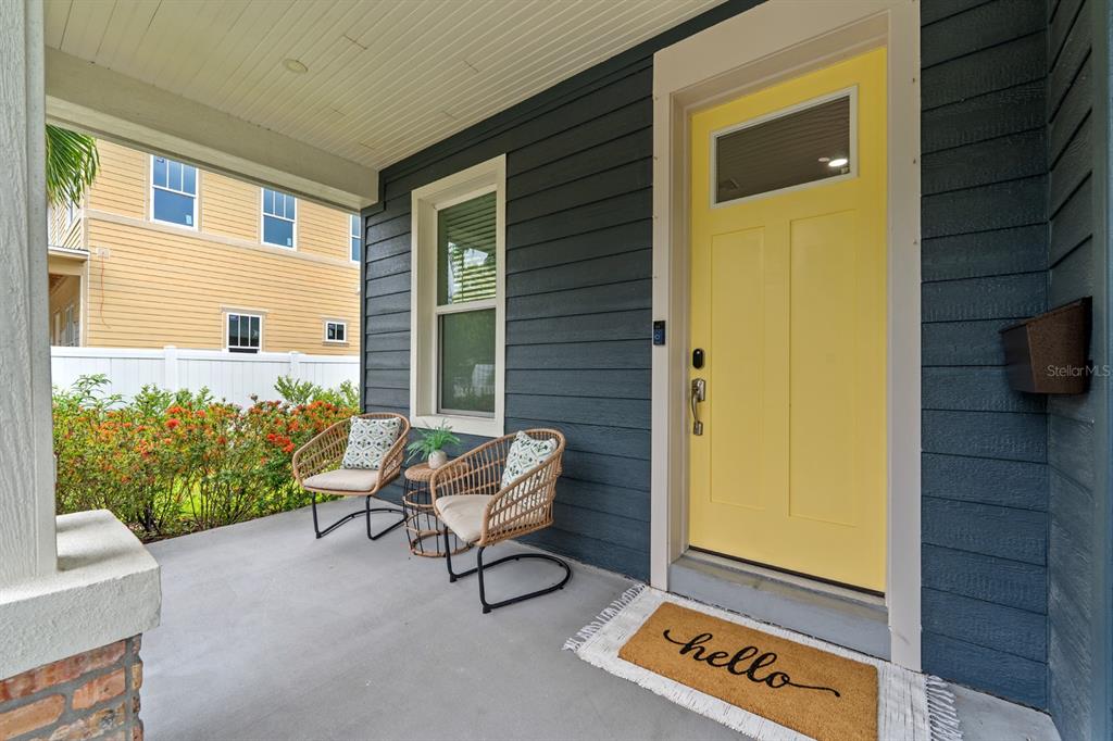 A front porch features a yellow door, two wicker chairs, and a hello doormat — 1028 5TH STREET N, ST PETERSBURG, FL