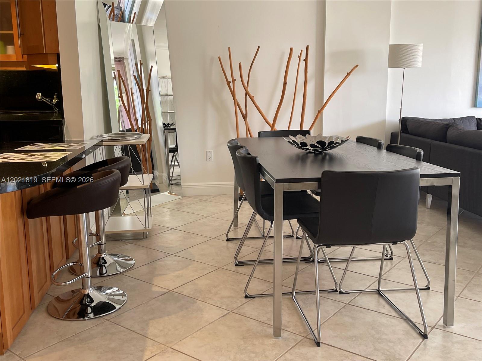 A dining area features a dark table with metal chairs, bar stools, and decorative branches — 199 Ocean Lane Dr # 413, Key Biscayne FL 33149, KEY BISCAYNE, FL