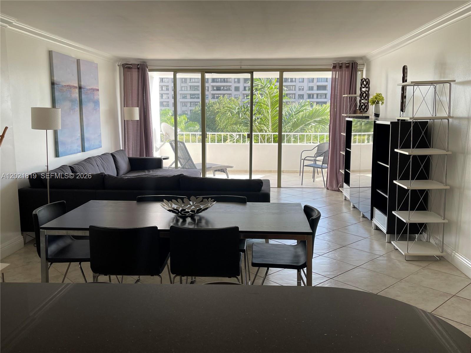 A living and dining room features a dark sofa, dining table, and balcony access — 199 Ocean Lane Dr # 413, Key Biscayne FL 33149, KEY BISCAYNE, FL