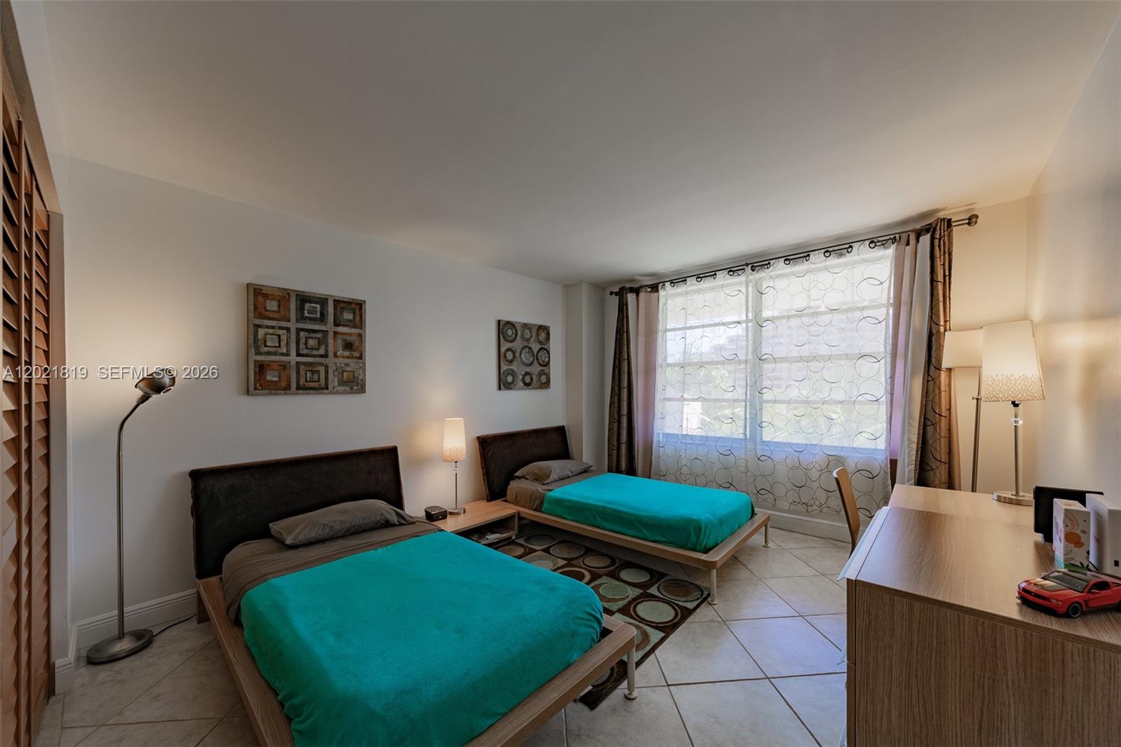 A bedroom features two twin beds with teal bedding, tile flooring, and a large window — 199 Ocean Lane Dr # 413, Key Biscayne FL 33149, KEY BISCAYNE, FL