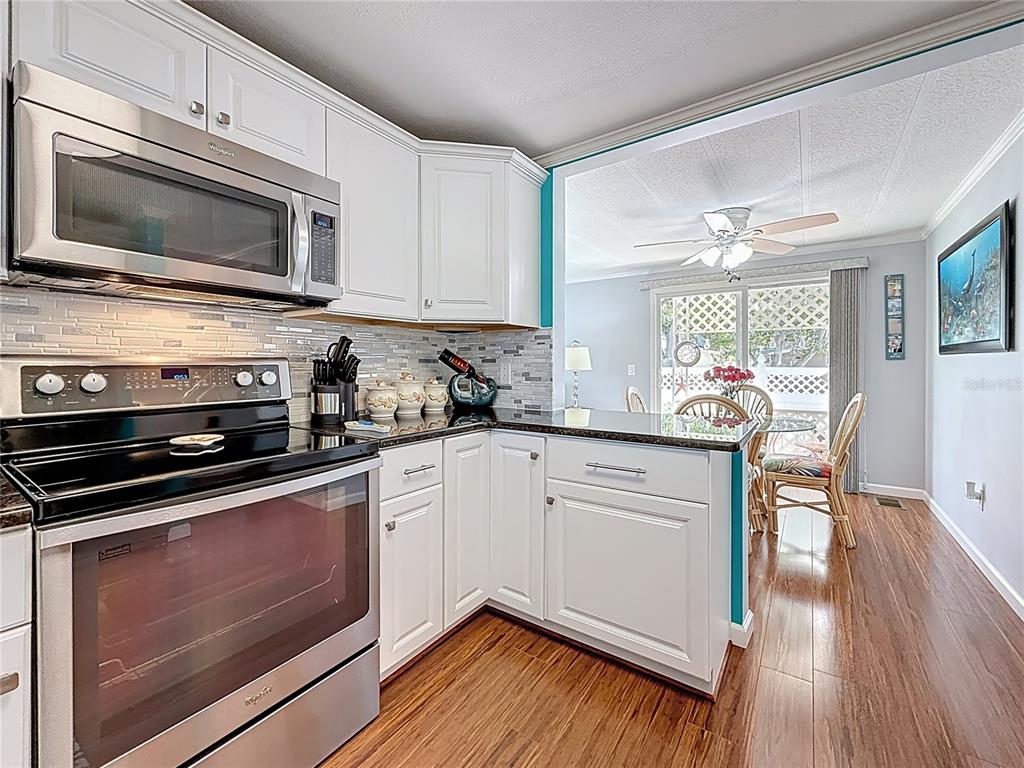 A kitchen with white cabinets, stainless steel appliances, and a view into a dining area — 7880 54TH AVENUE N UNIT 54, ST PETERSBURG, FL