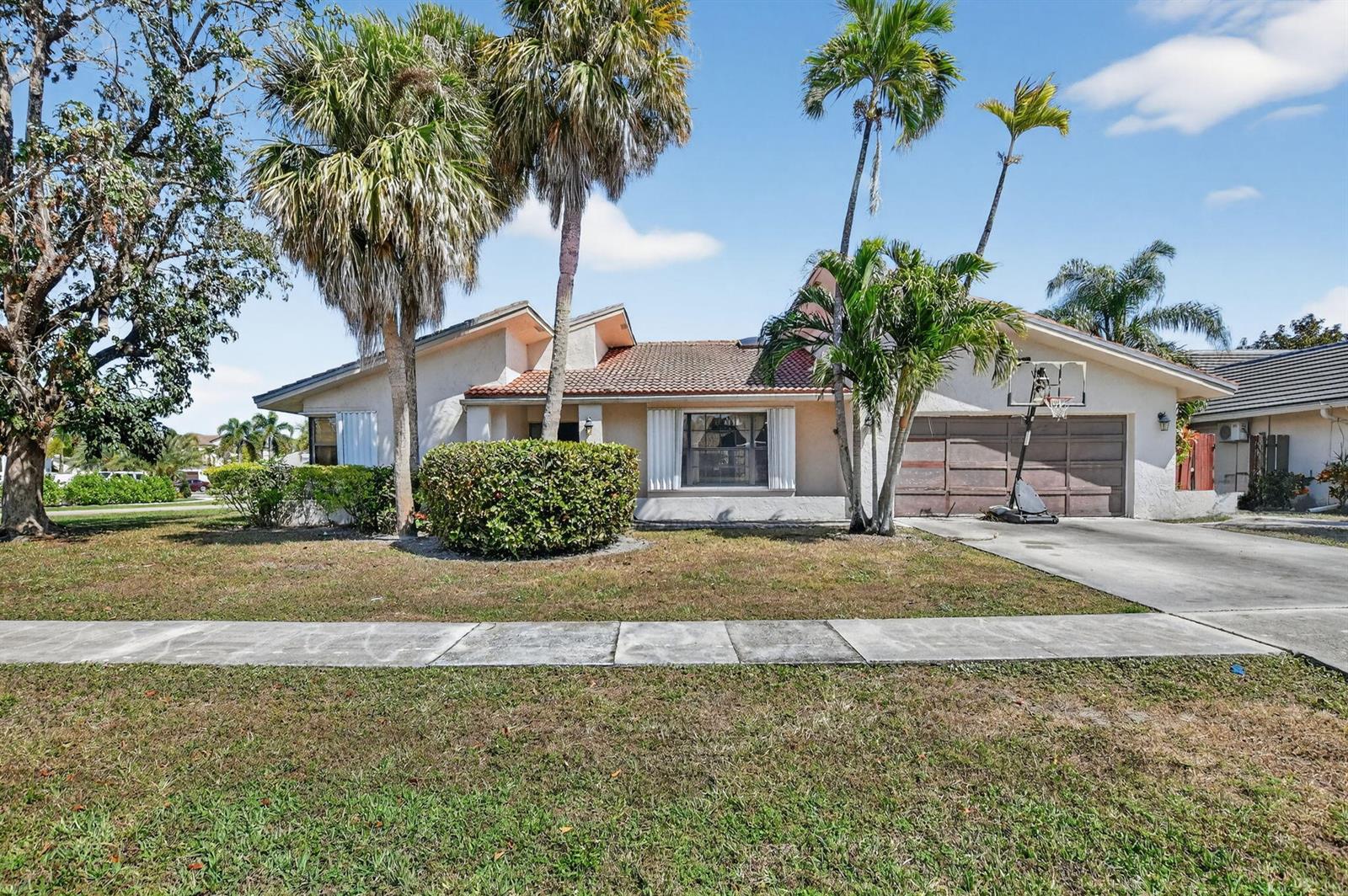 A single-story house with a tiled roof, palm trees, and a basketball hoop in front — 22220 Morning Glory Terrace, Boca Raton FL 33433, BOCA RATON, FL