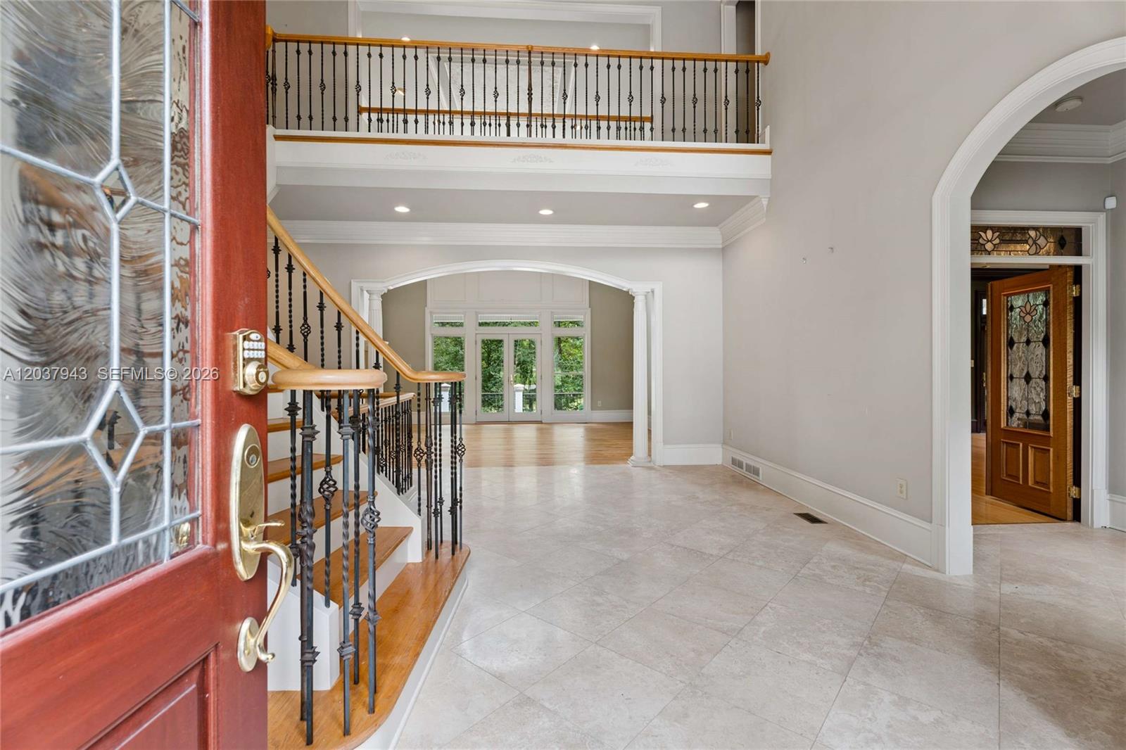 A foyer with a tile floor, a wooden staircase, and an arched entryway to another room — 1845 Kathy Whitworth Drive, GA 30517, GA