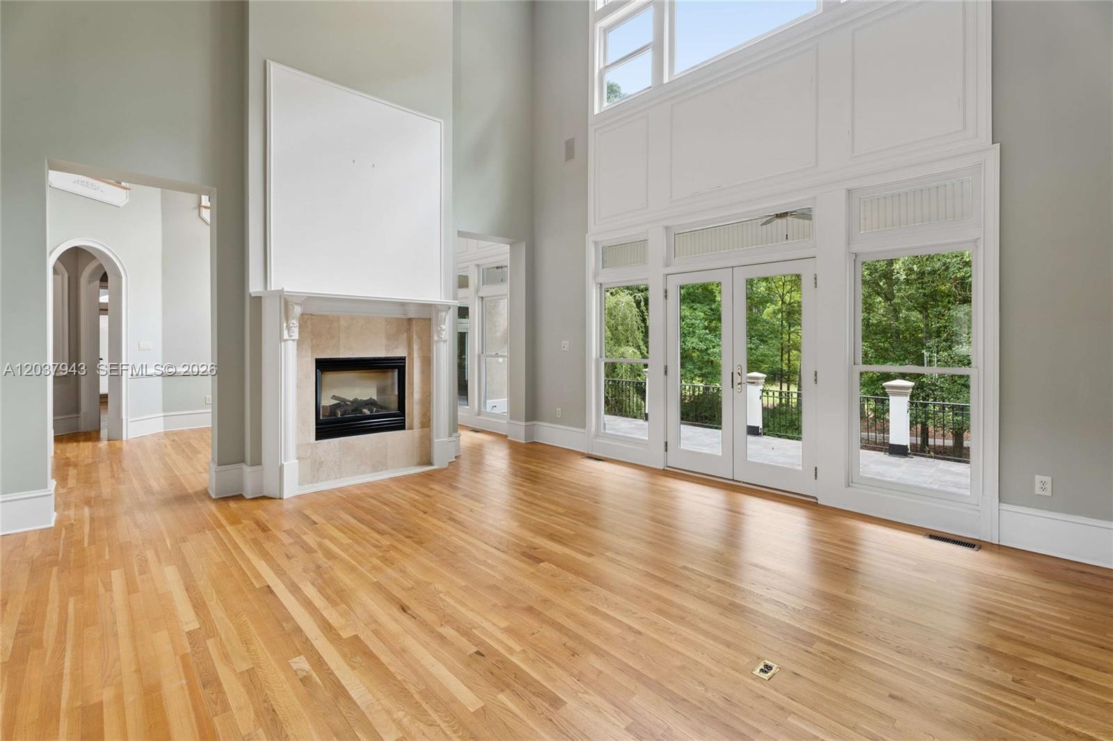A spacious living room features hardwood floors, a tall fireplace, and large glass doors — 1845 Kathy Whitworth Drive, GA 30517, GA