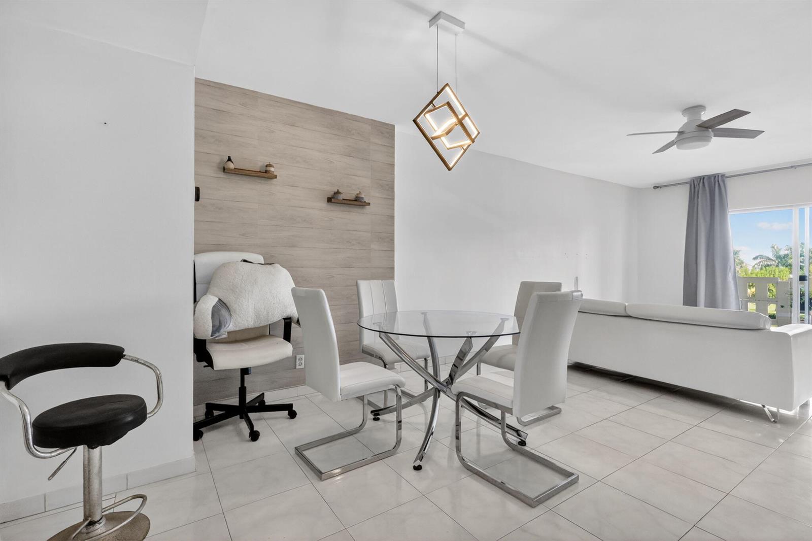 A dining area features a glass table, white chairs, and a wood-paneled accent wall — 4330 Hillcrest Drive # 302, Hollywood FL 33021, HOLLYWOOD, FL