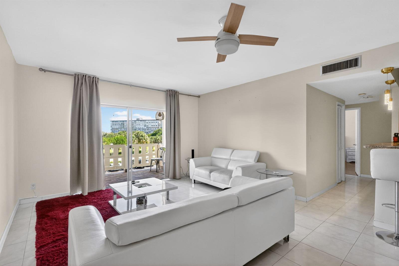 A living room features white leather sofas, a red rug, and a balcony with views — 4330 Hillcrest Drive # 302, Hollywood FL 33021, HOLLYWOOD, FL