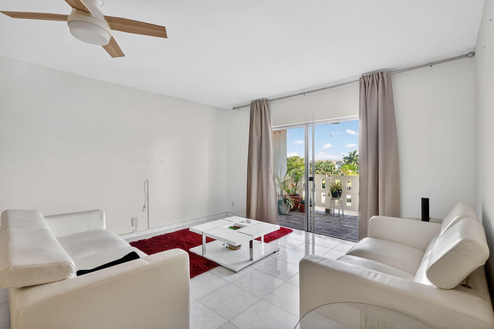 A living room features white leather sofas, a red rug, a coffee table, and a balcony — 4330 Hillcrest Drive # 302, Hollywood FL 33021, HOLLYWOOD, FL