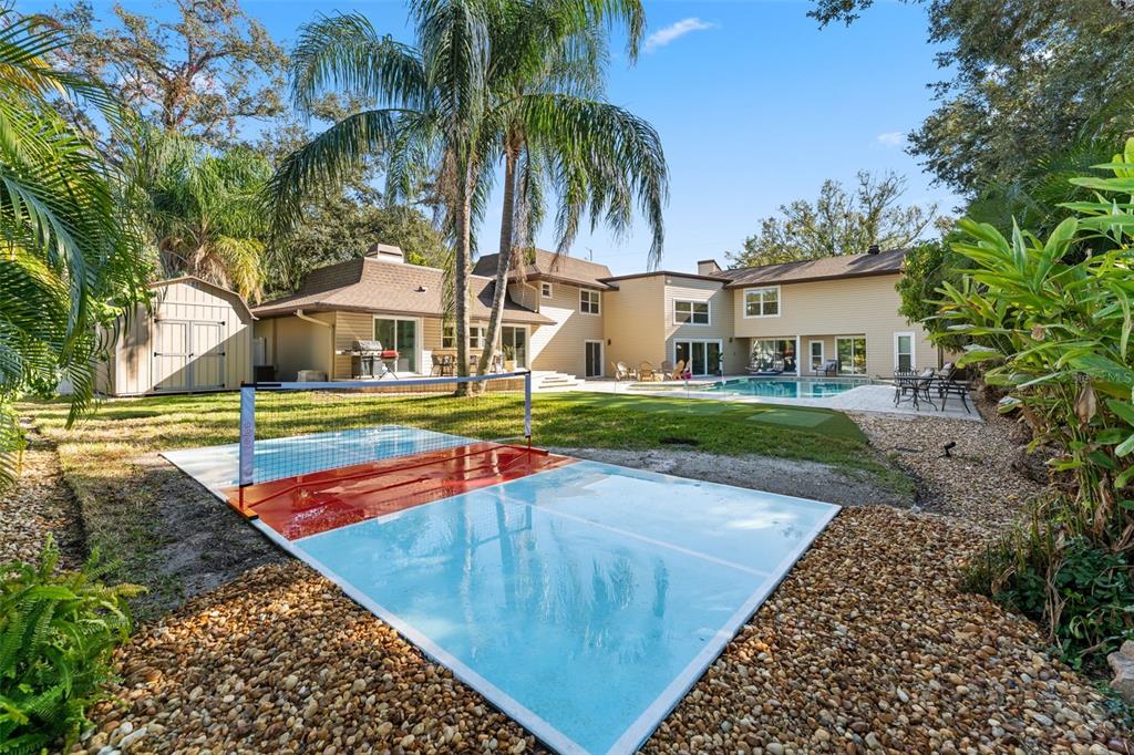 A backyard features a small pickleball court, a swimming pool, and a detached storage shed — 1584 OAK LANE, CLEARWATER, FL