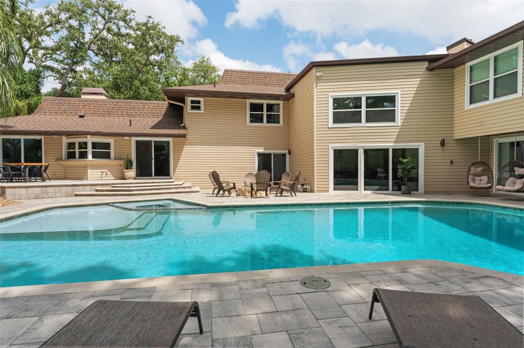 A swimming pool with a pink flamingo float sits in front of a two-story house — 1584 OAK LANE, CLEARWATER, FL