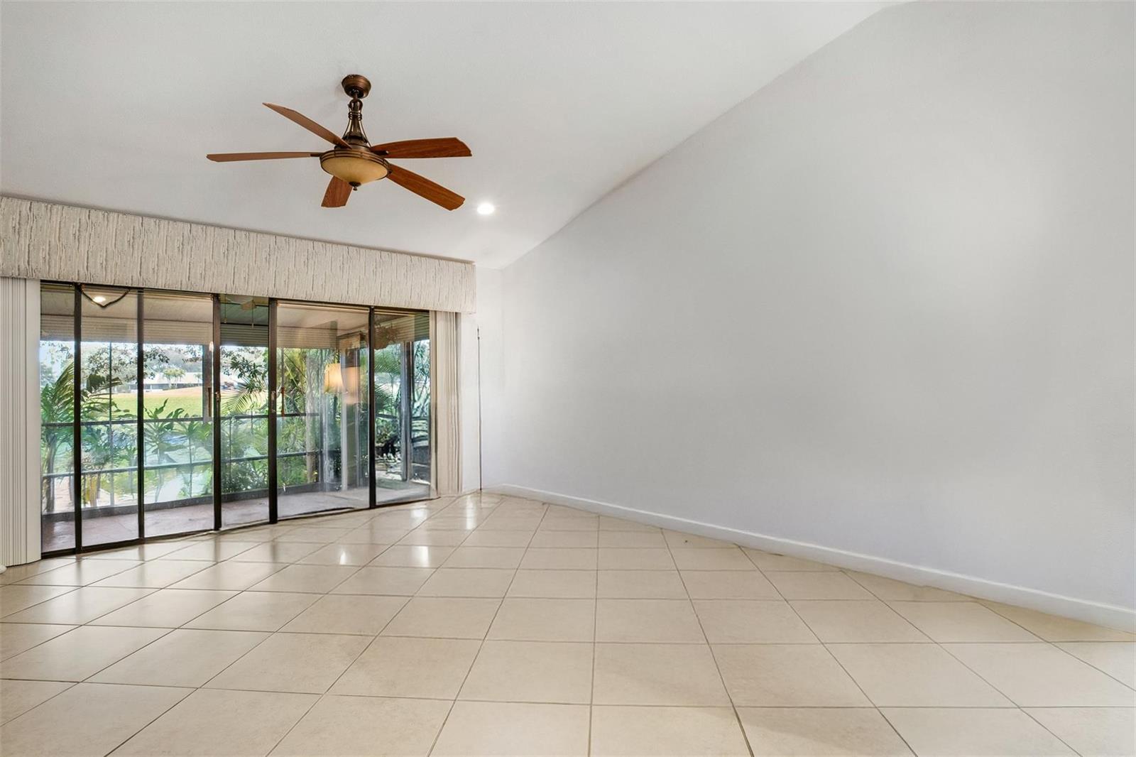 An empty room with white walls, tile floors, a ceiling fan, and sliding glass doors — 16131 Laurel Drive # 33, Weston FL 33326, WESTON, FL