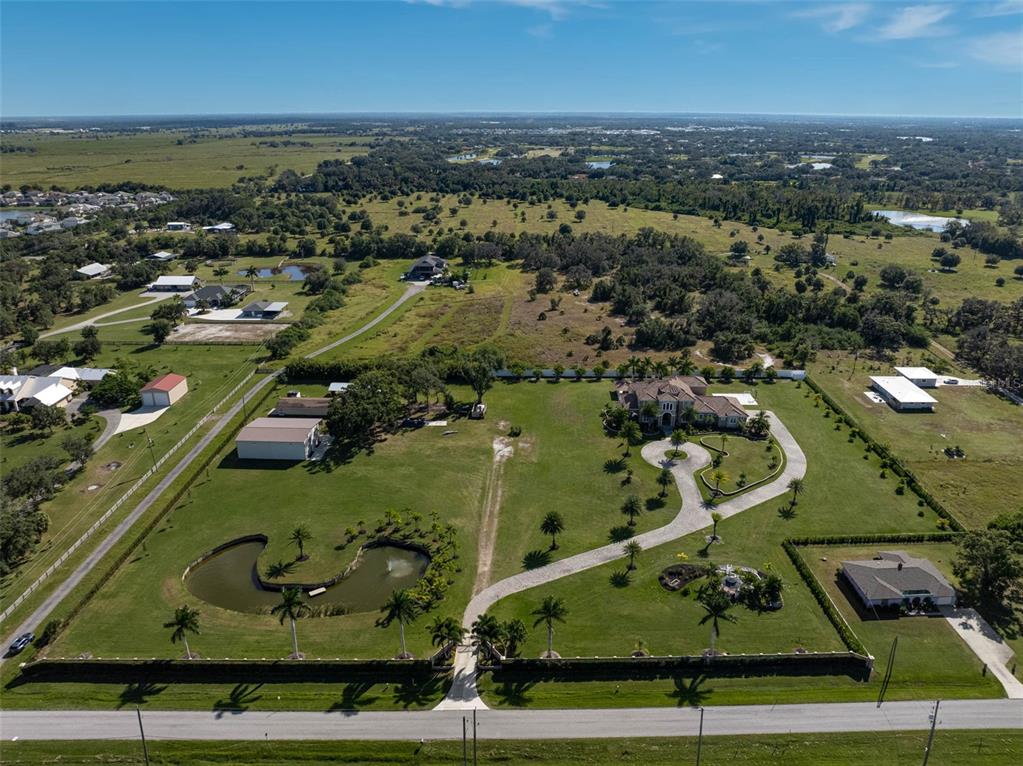 An aerial view shows a large house with a pond, circular driveway, and outbuildings — 6722 HAWKINS ROAD, SARASOTA, FL