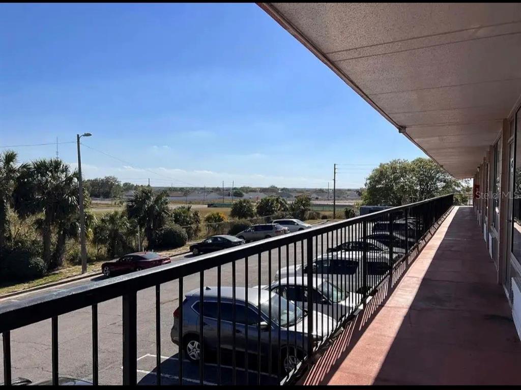 A view from a covered outdoor balcony overlooking a parking lot and a grassy field — 43420 HIGHWAY 27 UNIT 425, DAVENPORT, FL