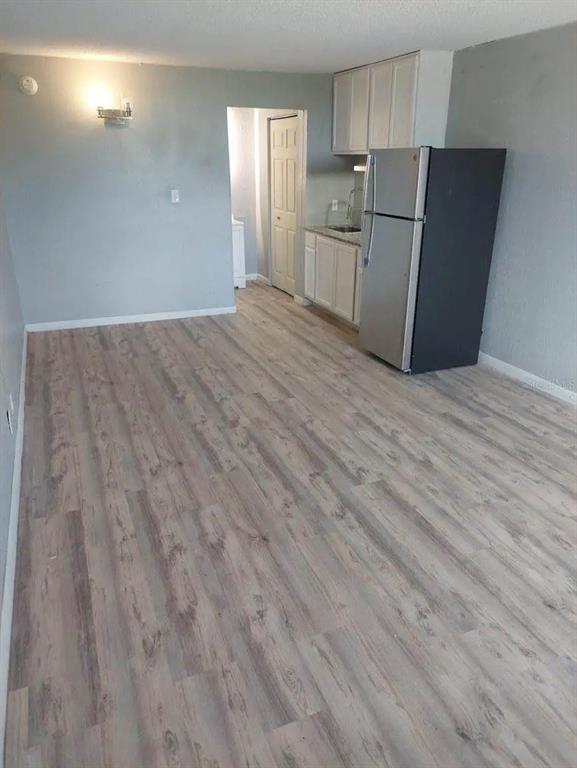 A room with light-colored wood-look flooring, a small kitchen area, and a stainless steel refrigerator — 43420 HIGHWAY 27 UNIT 425, DAVENPORT, FL