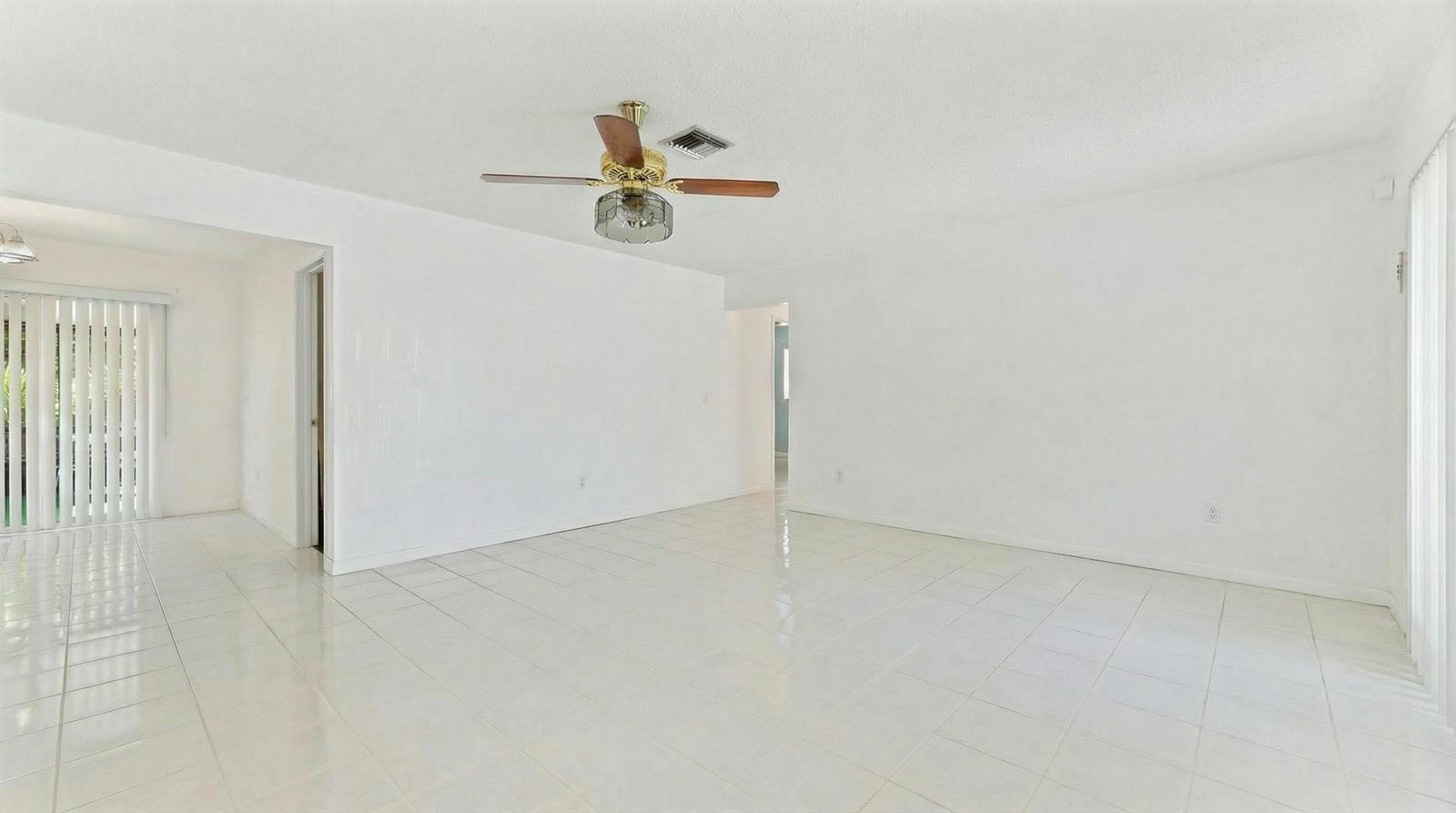 A bright, empty living room features white walls, white tile flooring, and a ceiling fan — 428 Alemeda Drive, Palm Springs FL 33461, PALM SPRINGS, FL