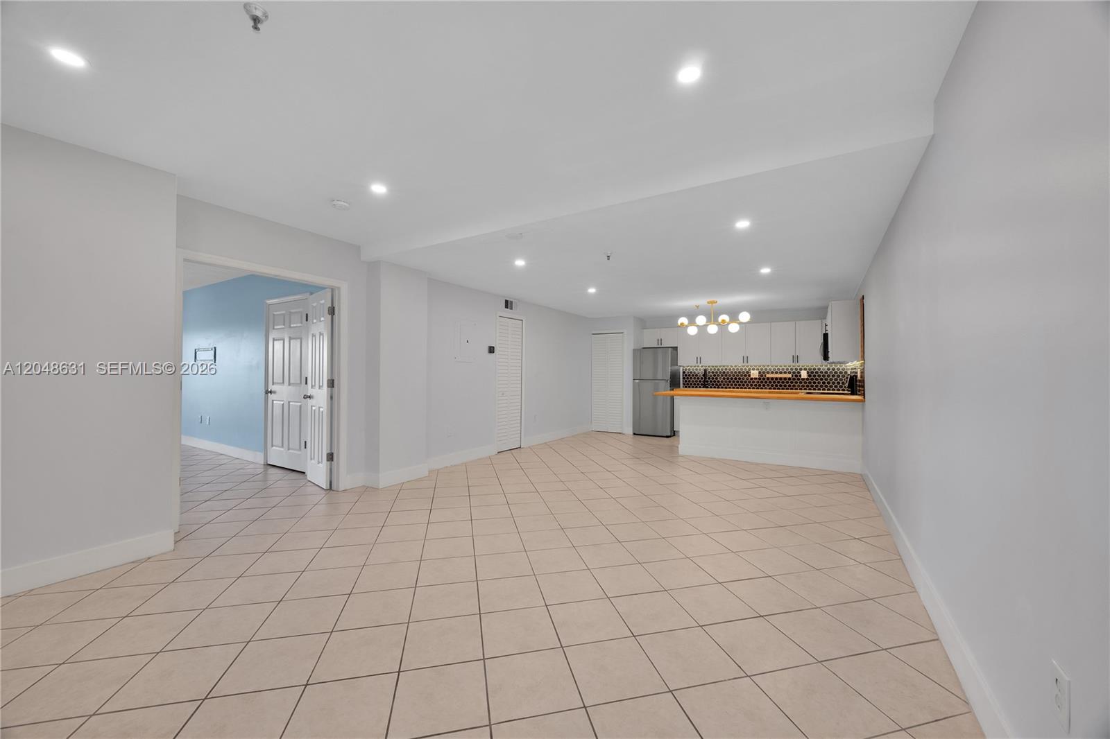 An open-concept living area features light-colored tile flooring, recessed lighting, and a kitchen with bar seating — 2734 Bird Ave # 301, Miami FL 33133, MIAMI, FL