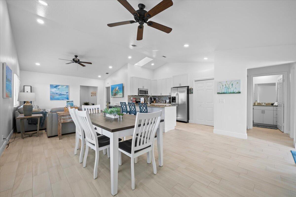 An open-concept dining area and kitchen feature white cabinetry, stainless steel appliances, and tile flooring — 6077 Francis Street, Jupiter FL 33458, JUPITER, FL