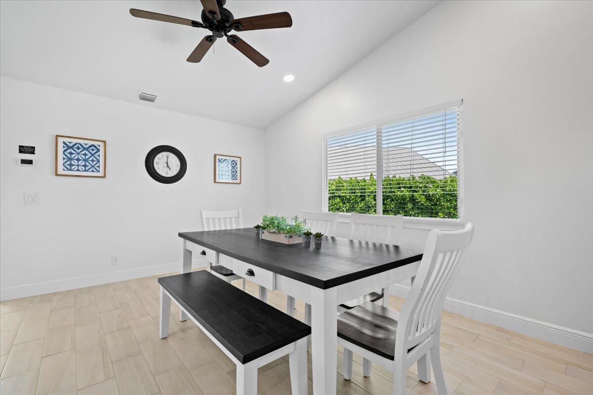 A dining room features a dark wood table with white chairs and a matching bench — 6077 Francis Street, Jupiter FL 33458, JUPITER, FL