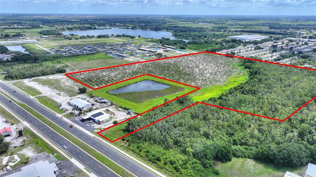 An aerial view shows a large plot of land outlined in red featuring a pond — U S HIGHWAY 27, DUNDEE, FL