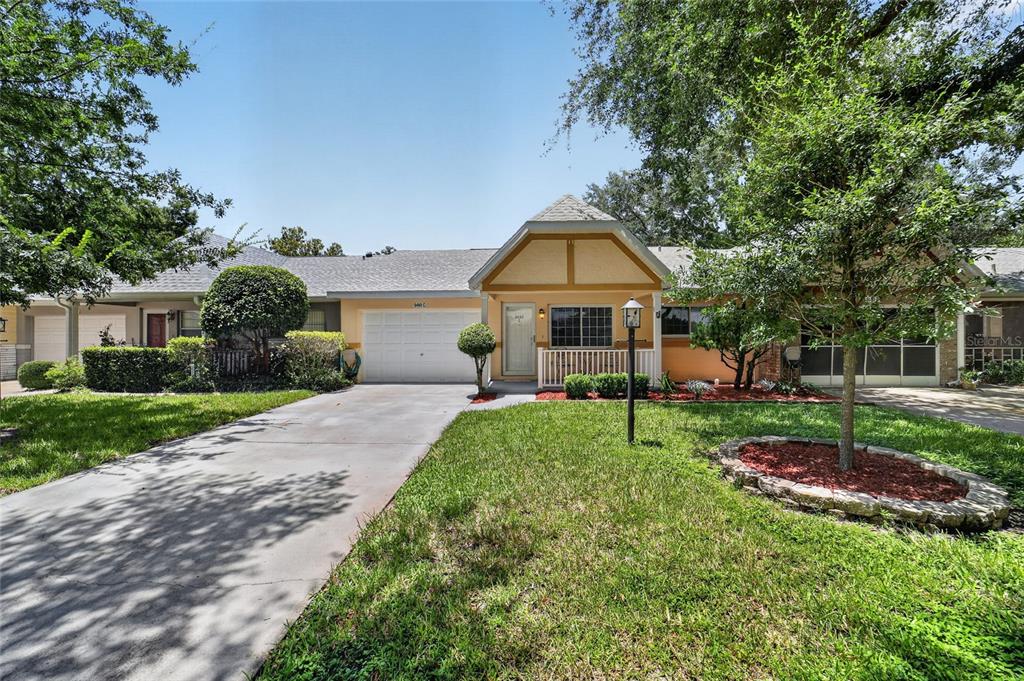 A single-story house with a white garage, tan stucco exterior, and a small front porch — 9490 SW 85TH AVENUE UNIT C, OCALA, FL