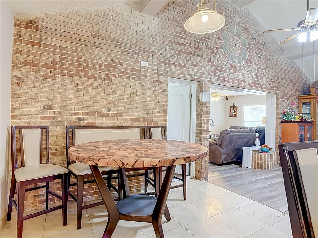 A dining area features a round wood-slice table against a large, vaulted brick wall — 1123 W HANCOCK DRIVE, DELTONA, FL