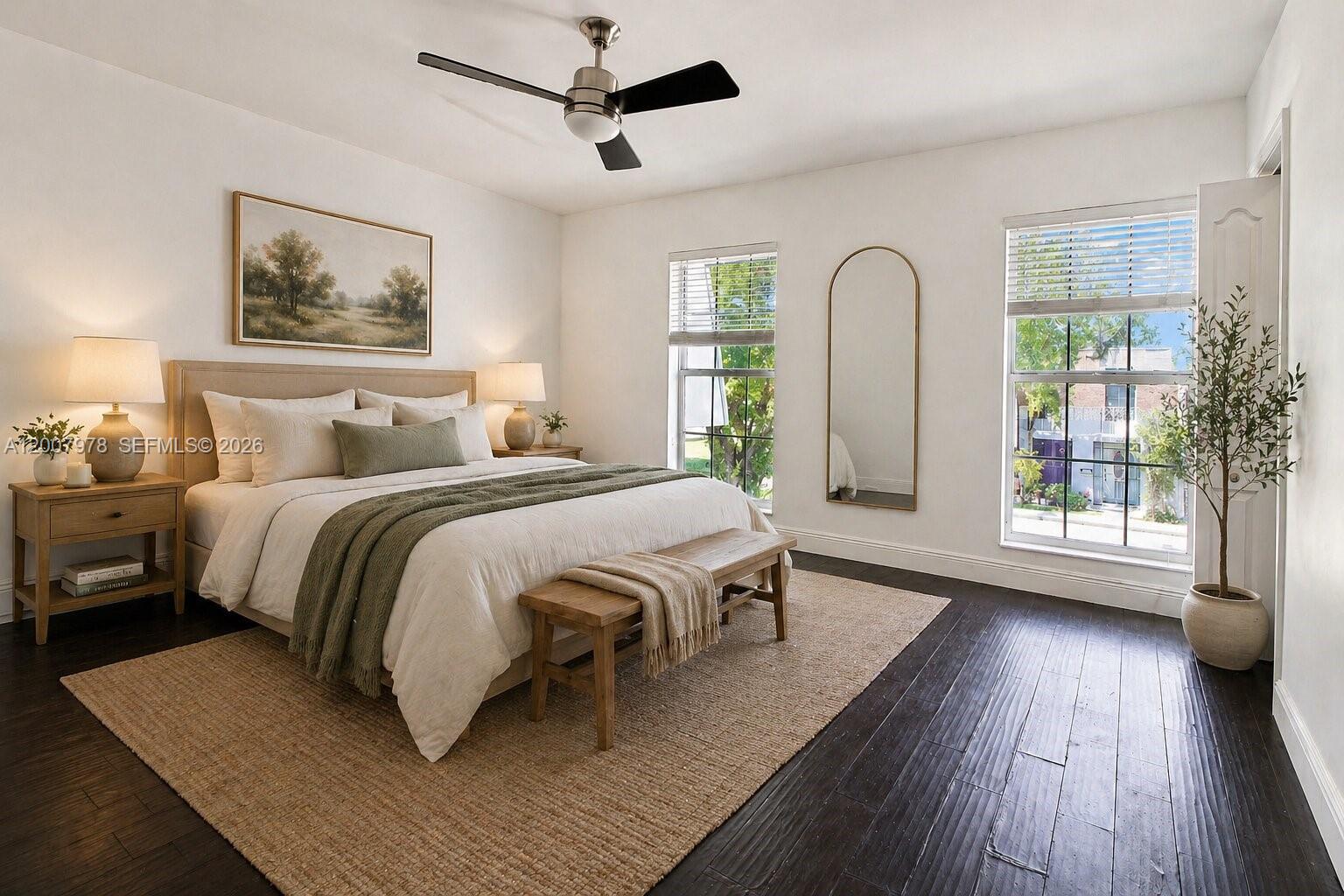 A bedroom features a bed with a green throw, dark wood floors, and two windows — 13501 NE 23rd Ct, North Miami FL 33181, NORTH MIAMI, FL