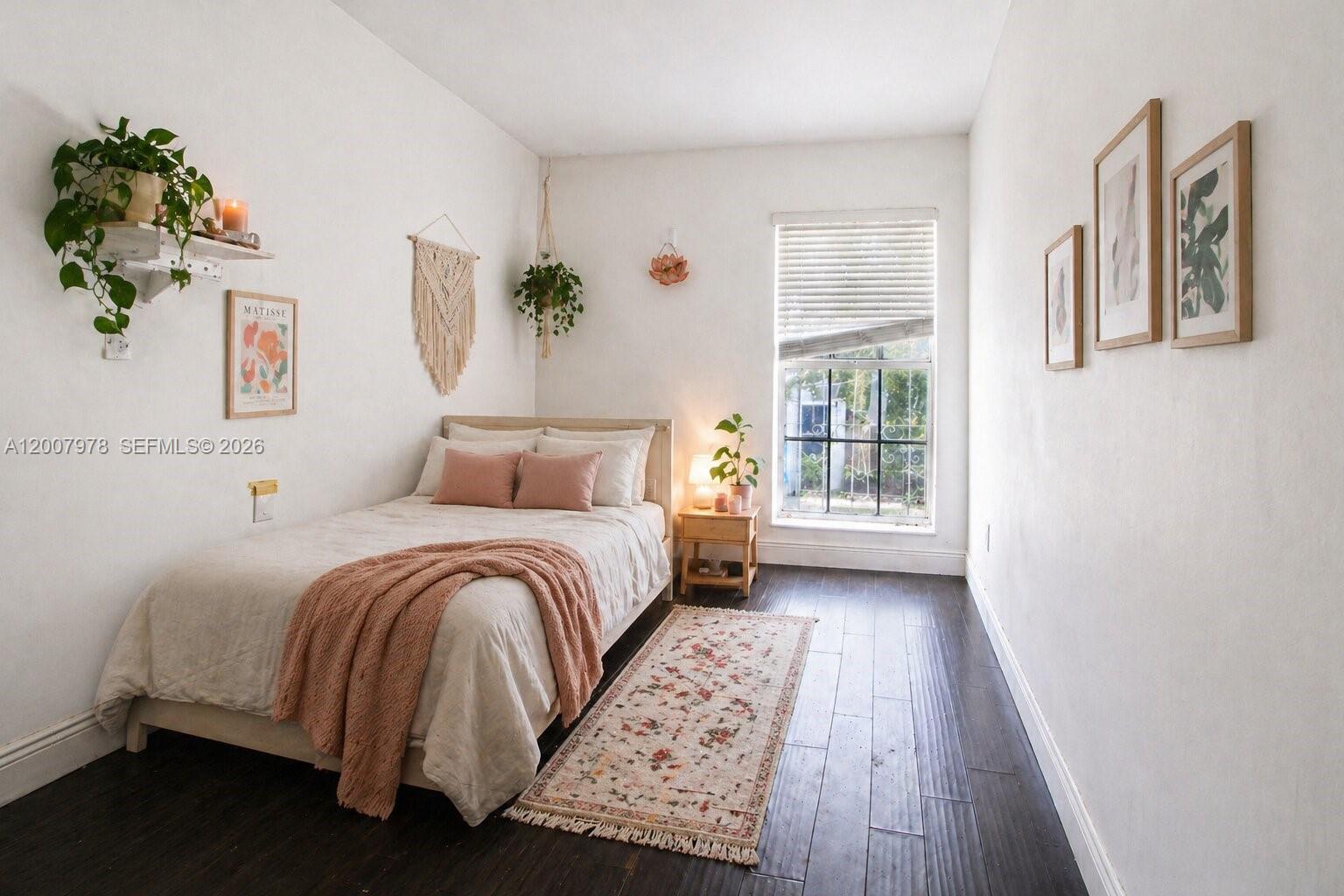 A bedroom features a bed with pink pillows, a window, and wood-look flooring — 13501 NE 23rd Ct, North Miami FL 33181, NORTH MIAMI, FL