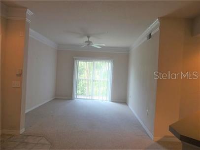 A carpeted living room features a ceiling fan and sliding glass doors leading outside — 5134 NORTHRIDGE ROAD UNIT 211, SARASOTA, FL