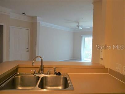 A kitchen sink with a stainless steel faucet overlooks an open living area — 5134 NORTHRIDGE ROAD UNIT 211, SARASOTA, FL