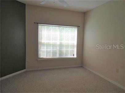 A bedroom with beige carpet, light walls, a dark accent wall, and a large window — 5134 NORTHRIDGE ROAD UNIT 211, SARASOTA, FL
